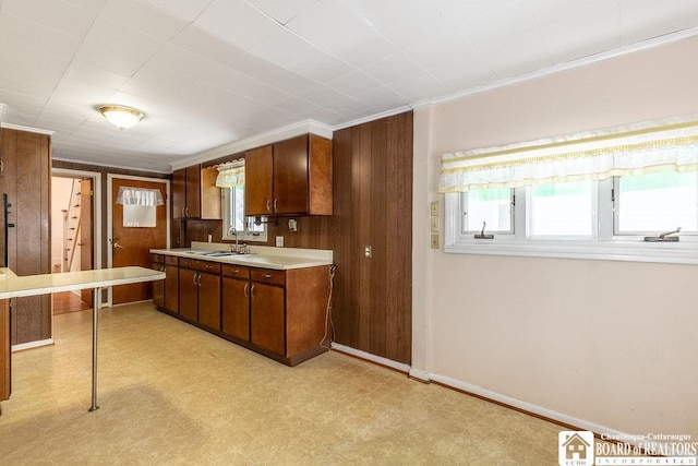 kitchen featuring light floors, baseboards, light countertops, and a sink