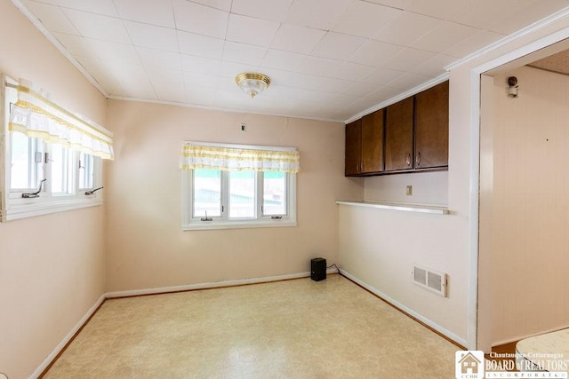 empty room featuring baseboards, visible vents, crown molding, and light floors