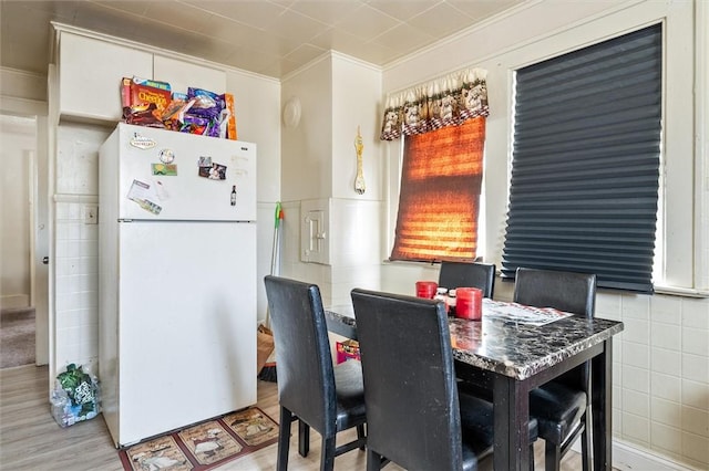 dining area featuring wainscoting, wood finished floors, tile walls, and crown molding