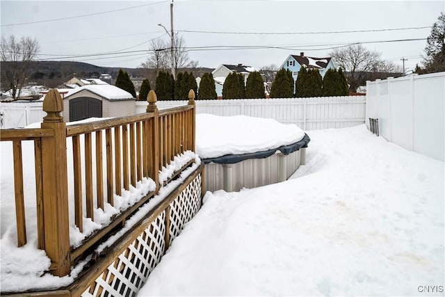 yard covered in snow featuring an outbuilding, a storage unit, and a fenced backyard