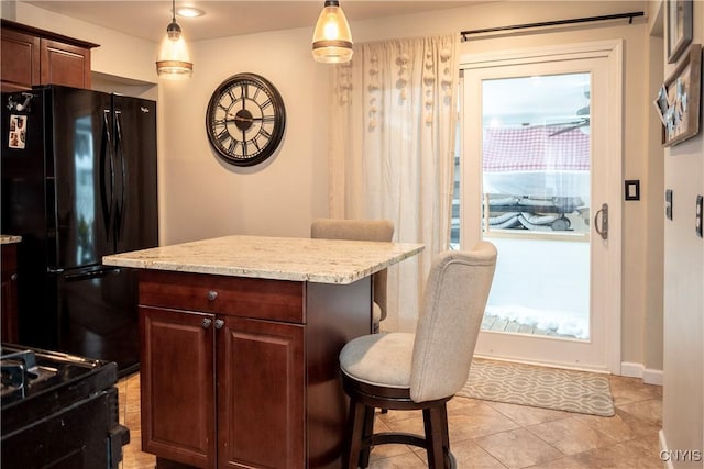 kitchen featuring plenty of natural light, a breakfast bar, a center island, freestanding refrigerator, and pendant lighting