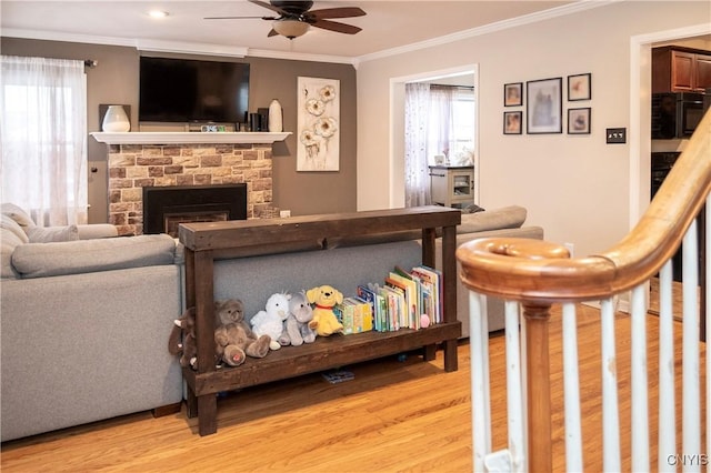 living area featuring a healthy amount of sunlight, light wood finished floors, a fireplace, and crown molding