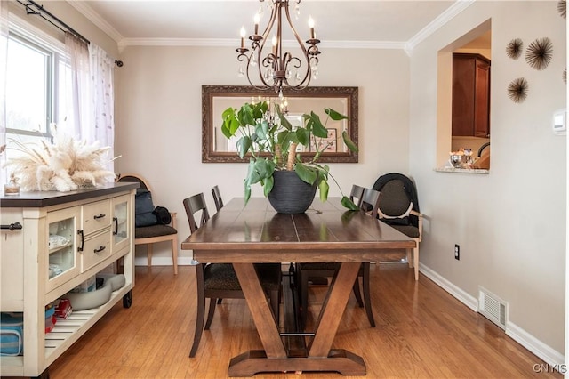 dining room with light wood-type flooring, visible vents, crown molding, and baseboards