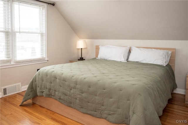 bedroom featuring vaulted ceiling, wood finished floors, visible vents, and baseboards