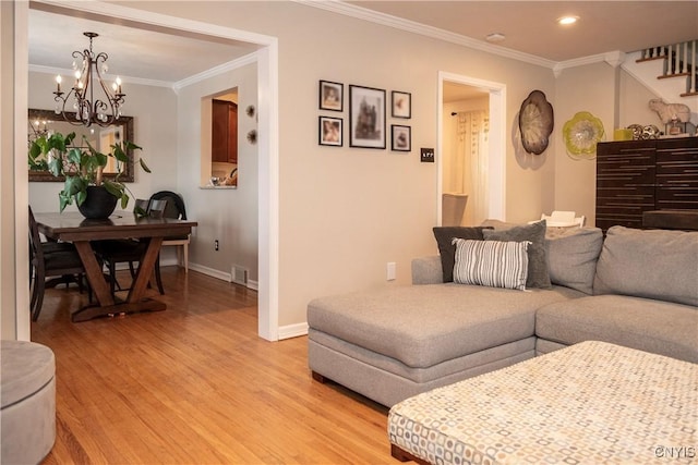 living area with light wood-style floors, ornamental molding, baseboards, and an inviting chandelier