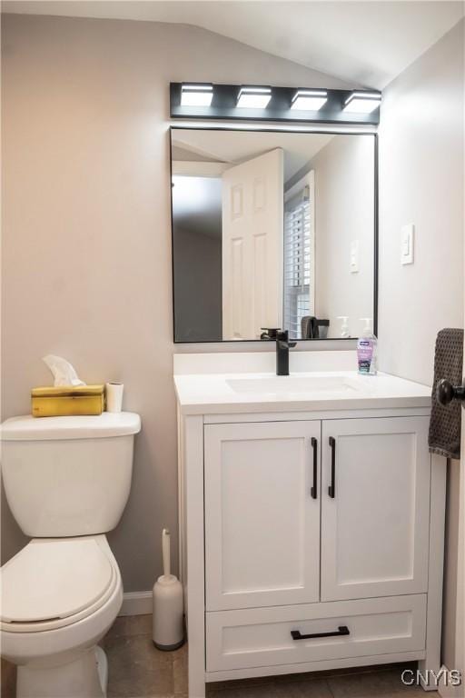 half bath with lofted ceiling, tile patterned floors, toilet, and vanity