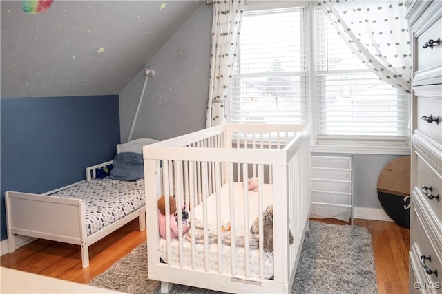 bedroom with lofted ceiling, baseboards, and wood finished floors