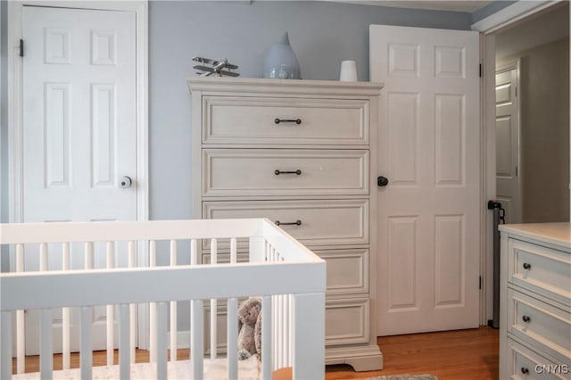 bedroom featuring a nursery area and light wood finished floors