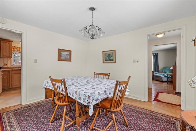 dining room with an inviting chandelier, light wood-style flooring, and baseboards