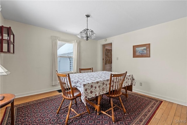 dining area featuring an inviting chandelier, wood finished floors, and baseboards