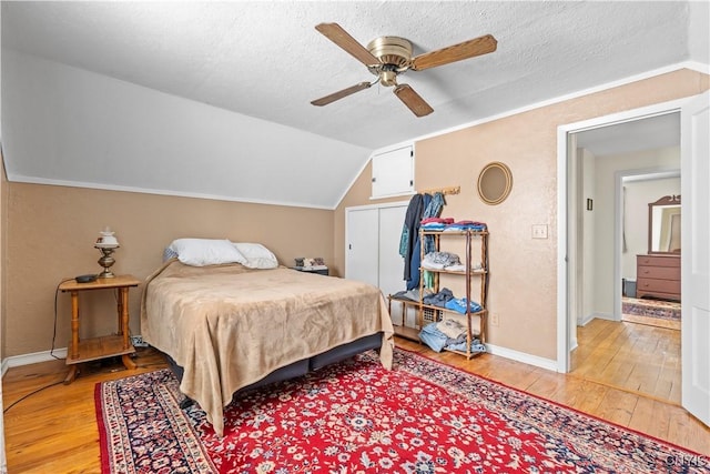 bedroom featuring lofted ceiling, a textured ceiling, light wood-type flooring, and baseboards