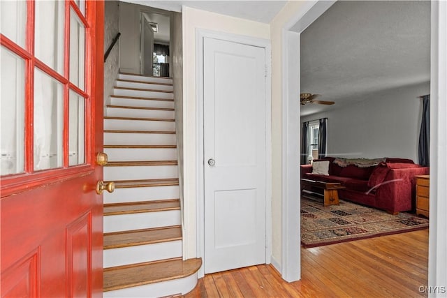 stairs with wood finished floors and a ceiling fan