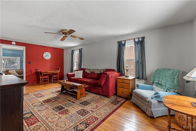 living area featuring hardwood / wood-style flooring, ceiling fan, and a textured ceiling