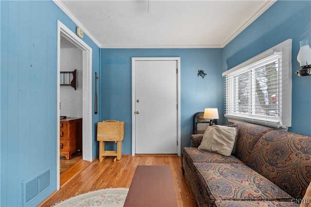 living room featuring visible vents, crown molding, and light wood-style flooring