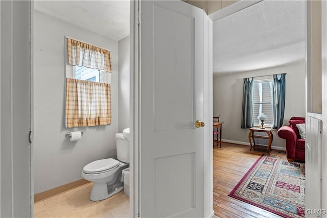 bathroom featuring a textured ceiling, wood finished floors, toilet, and baseboards