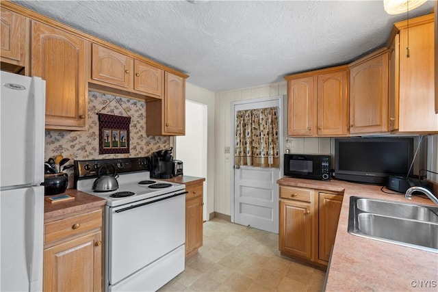 kitchen featuring a textured ceiling, white appliances, a sink, light countertops, and light floors