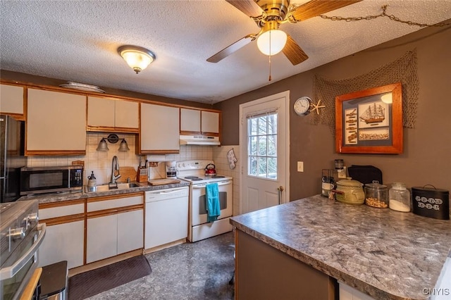 kitchen featuring white appliances, a sink, a textured ceiling, under cabinet range hood, and backsplash