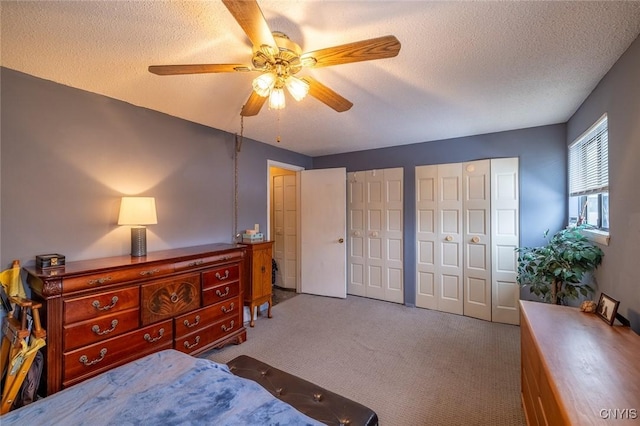 carpeted bedroom featuring ceiling fan, a textured ceiling, and multiple closets