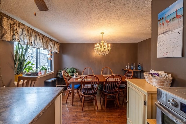 dining space featuring a textured ceiling, wood finished floors, and ceiling fan with notable chandelier