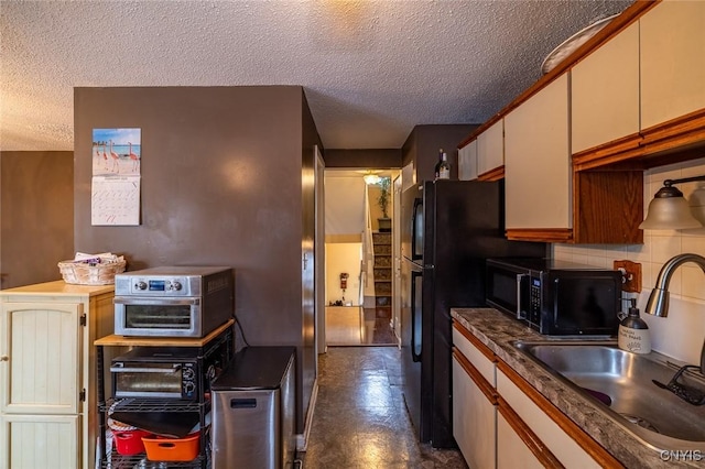 kitchen featuring black microwave, dark floors, a textured ceiling, a sink, and backsplash