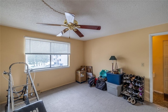 workout area featuring carpet floors, baseboards, a ceiling fan, and a textured ceiling