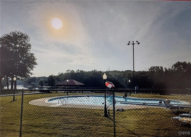 view of swimming pool featuring a yard, fence, and community basketball court