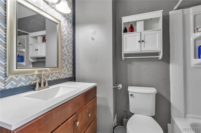 bathroom featuring toilet, walk in shower, decorative backsplash, and vanity