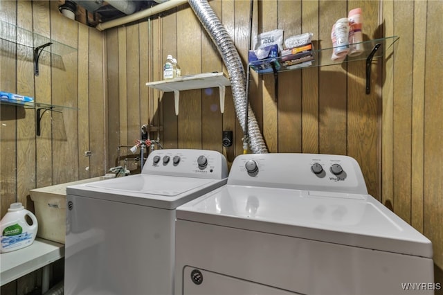 clothes washing area featuring wood walls and washing machine and clothes dryer