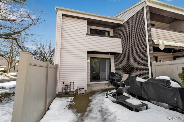 snow covered property featuring fence and a balcony