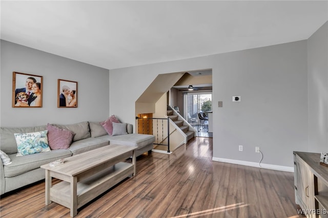 living room featuring stairs, dark wood finished floors, and baseboards