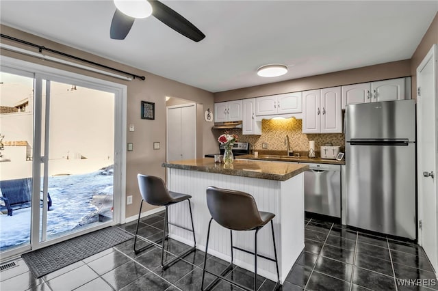 kitchen featuring decorative backsplash, dark tile patterned flooring, appliances with stainless steel finishes, white cabinetry, and a sink