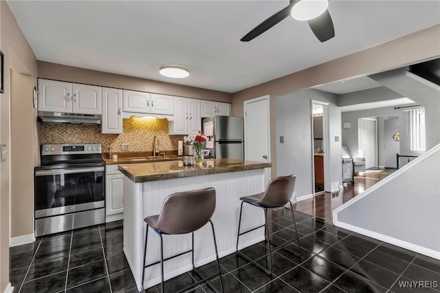 kitchen featuring stainless steel appliances, dark countertops, white cabinets, and under cabinet range hood