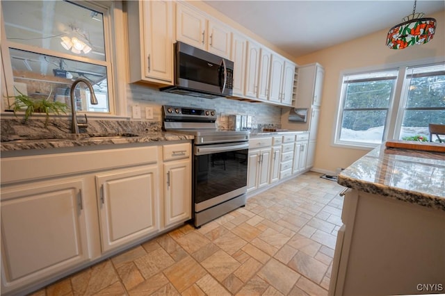 kitchen with dark stone counters, stainless steel appliances, stone finish floor, and decorative backsplash