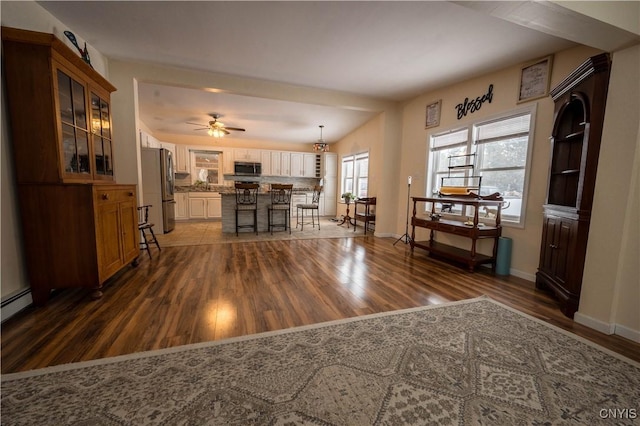 interior space with ceiling fan, baseboards, and dark wood finished floors