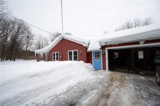 snow covered property with an attached garage and driveway