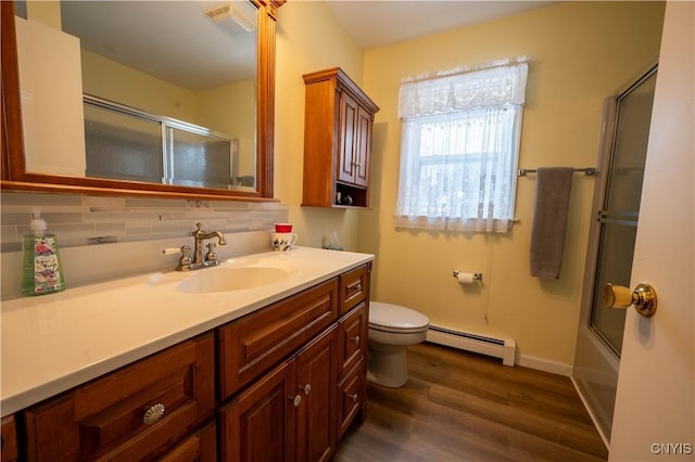 full bath with tasteful backsplash, toilet, shower / bath combination with glass door, wood finished floors, and a baseboard heating unit