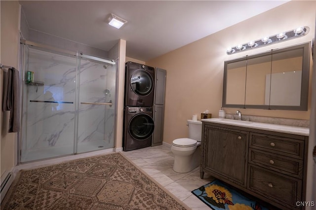 bathroom featuring toilet, vanity, marble finish floor, a marble finish shower, and stacked washer and clothes dryer