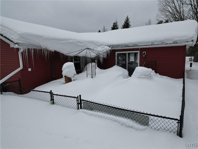 snow covered property with fence