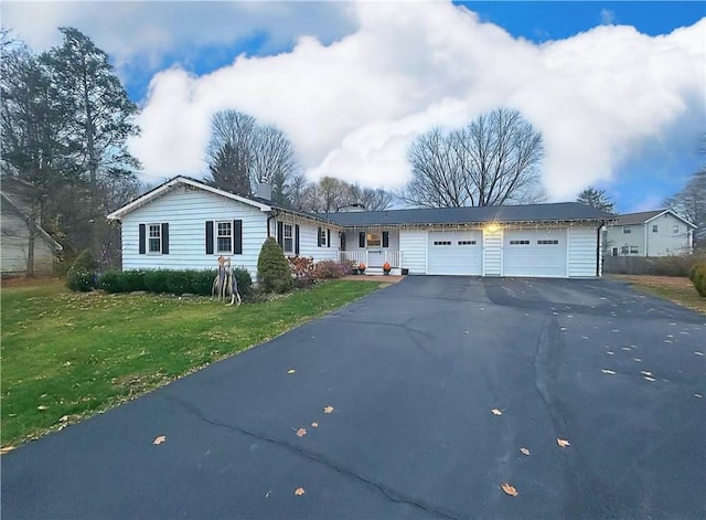 ranch-style home with an attached garage, aphalt driveway, and a front lawn