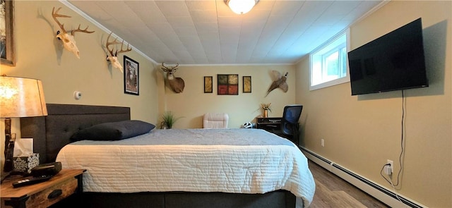 bedroom featuring a baseboard heating unit, wood finished floors, and ornamental molding