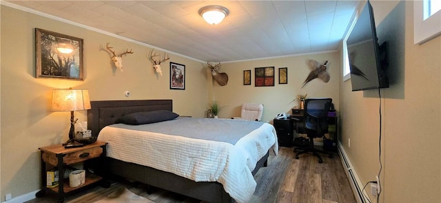 bedroom with a baseboard radiator, ornamental molding, and wood finished floors