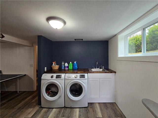 washroom with dark wood-type flooring, a sink, washer and dryer, cabinet space, and wet bar