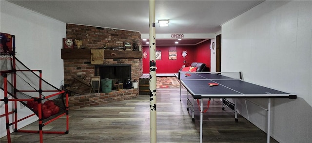 game room with a brick fireplace, baseboard heating, and wood finished floors