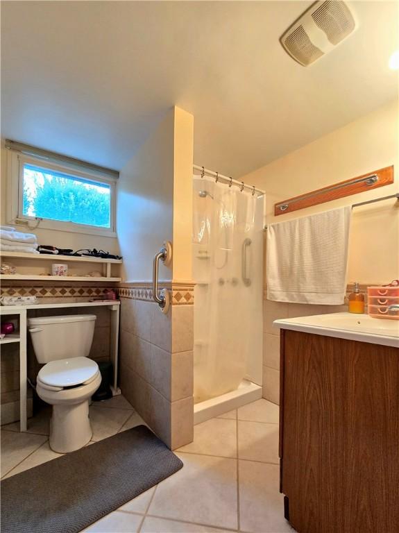 full bath featuring toilet, visible vents, tile walls, tile patterned floors, and a stall shower