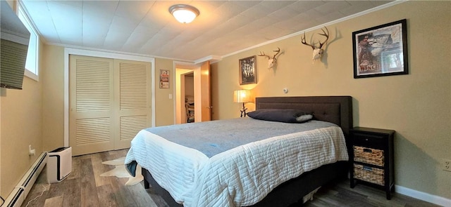 bedroom with a closet, ornamental molding, baseboard heating, and wood finished floors