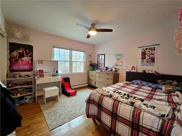 bedroom with ceiling fan, baseboard heating, and wood finished floors