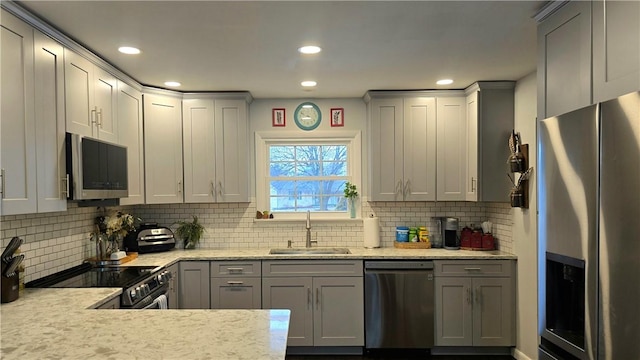 kitchen with stainless steel appliances, backsplash, a sink, and gray cabinetry