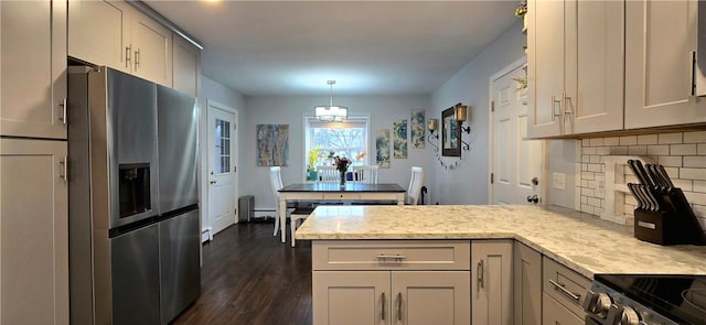 kitchen with decorative backsplash, dark wood-style floors, appliances with stainless steel finishes, light stone counters, and a peninsula