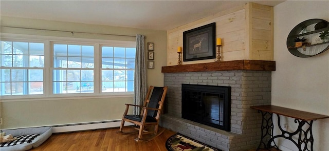 sitting room featuring a brick fireplace and wood finished floors