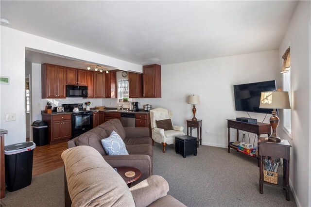 carpeted living room featuring visible vents, a sink, and baseboards